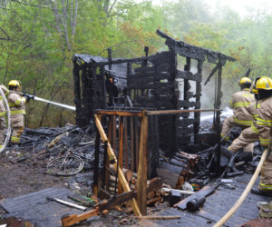 Bristol firefighters hit remaining hot spots after a fire destroyed a one-story shack near the intersection of Coggins Road and Route 32 in the Round Pond area of Bristol on Sunday afternoon, June 5. (Maia Zewert photo)