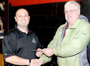 Lincoln Academy Athletic Director K.J. Anastasio presents a $185 check to Walter Hilton for winning the Cheney Insurance Shootout in January 2012. Hilton graduated from Lincoln Academy in 1966 and was a lifelong supporter of the academy.