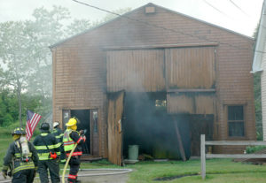 Firefighters were able to prevent a boathouse fire from spreading to a house only feet away, at right. (Alexander Violo photo)