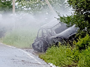 Only a shell remains after a car crashed into a utility pole and caught fire on Ridge Road (Route 215) in Newcastle on Saturday, July 2. Firefighters controlled the fire, but had to wait for a Central Maine Power Co. crew because of numerous live wires downed due to the crash. (Greg Latimer photo)