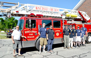 From left: Assistant Fire Chief Nick Merry, James Pray, Kevin Brewer, Kyle Viele, Devin Grover, Steven Smith, Capt. Nick Grover, Brycson Grover, and Chris Cossette stand in front of Ladder 1 on Monday, July 4. The truck is back in service after nearly a year away for repairs. (Charlotte Boynton photo)