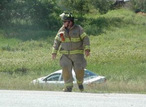 A Nobleboro firefighter works at the scene of a three-vehicle accident on Route 1 the afternoon of Monday, July 11. One of the three vehicles is in the ditch behind him. (Alexander Violo photo)