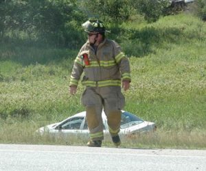 A Nobleboro firefighter works at the scene of a three-vehicle accident on Route 1 the afternoon of Monday, July 11. One of the three vehicles is in the ditch behind him. (Alexander Violo photo)