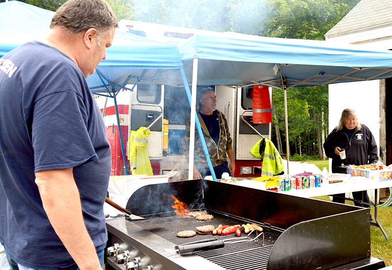 Dresden Assistant Fire Chief Ron Theriault flips a burger and cooks hot dogs to help raise money for the Dresden Fire Department. (Haley Bascom photo)