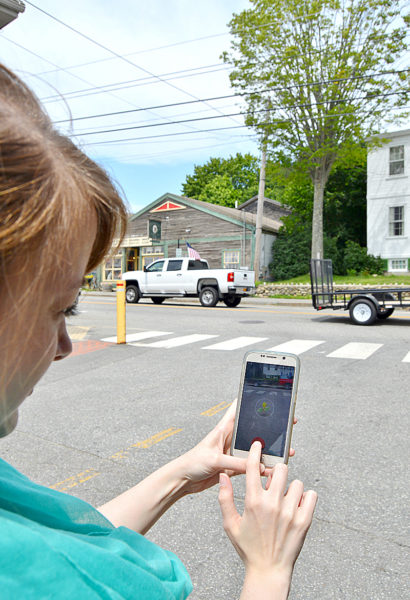 Pokemon Go enthusiast Amber Clark, of Newcastle, attempts to capture a Pokemon called Bellsprout by throwing a Poke Ball at it across the street from S. Fernald's Country Store in downtown Damariscotta on Monday, July 18. (Haley Bascom photo)