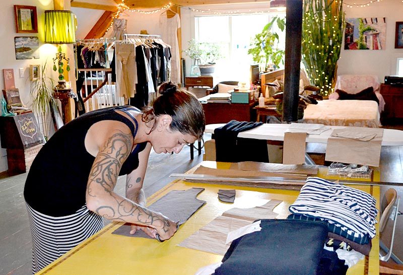 Katrina Kelley, owner and seamstress of Amphitrite Studio Clothing Co., cuts a tank top for her clothing line in her Newcastle home. Kelley uses natural and organic fibers for her women's clothing line, including linen, cotton, and bamboo. (Maia Zewert photo)