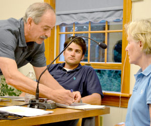 Mook Sea Farms Inc. owner Bill Mook explains the boundary of his proposed aquaculture lease to Sigrid Sproul while Jeff Auger, farm manager for Mook Sea Farms, looks on during a hearing at the South Bristol town office Wednesday, July 13. (Maia Zewert photo)