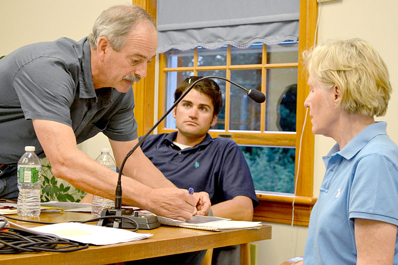 Mook Sea Farms Inc. owner Bill Mook explains the boundary of his proposed aquaculture lease to Sigrid Sproul while Jeff Auger, farm manager for Mook Sea Farms, looks on during a hearing at the South Bristol town office Wednesday, July 13. (Maia Zewert photo)