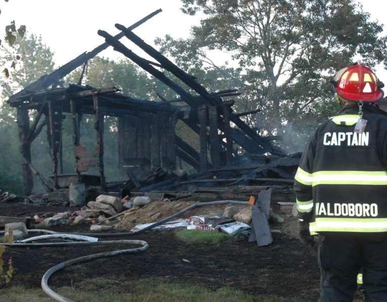 A Waldoboro firefighter looks on as crews finish up work at the scene of a house fire at 99 Atlantic Highway. There were no injuries, but the home was a total loss, according to Waldoboro Assistant Fire Chief William Maxwell. (Alexander Violo photo)