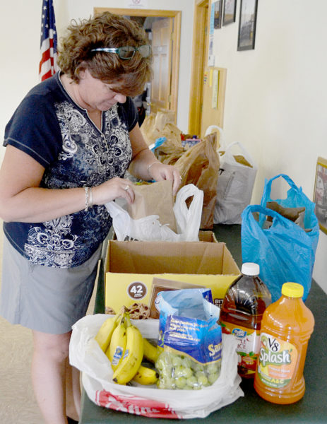 Caring for Kids President Jenny Pendleton inspects a food package prior to delivery. The nonprofit is providing weekly packages of food to 16 families in Bristol throughout the summer. (Maia Zewert photo)