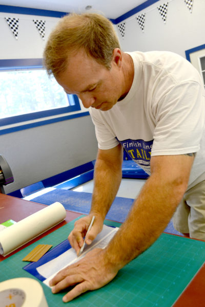 Finish Line Detailing President Sean McGregor cuts out vinyl letters. The shop at 74 Biscay Road in Damariscotta recently added a custom vinyl and graphics service. (Maia Zewert photo)