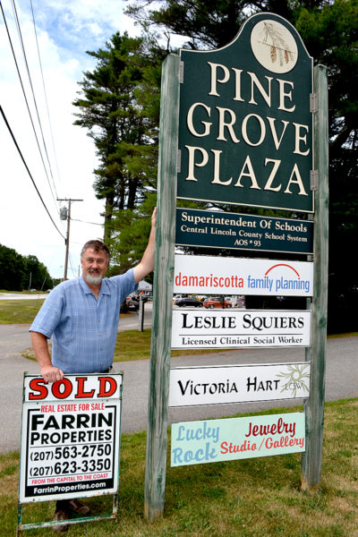 Farrin Properties owner Wayne Farrin stands next to the sign for Pine Grove Plaza at 767 Main St. in Damariscotta. Farrin Properties recently purchased the 23-acre property, which includes the office space, an attached house and garage, and a second garage. (Maia Zewert photo)