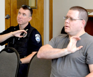 Damariscotta Police Officers Erick Halpin (left) and Jim Dotson practice the sign for police officer during a sign language training session Tuesday, Aug. 2. (Maia Zewert photo)