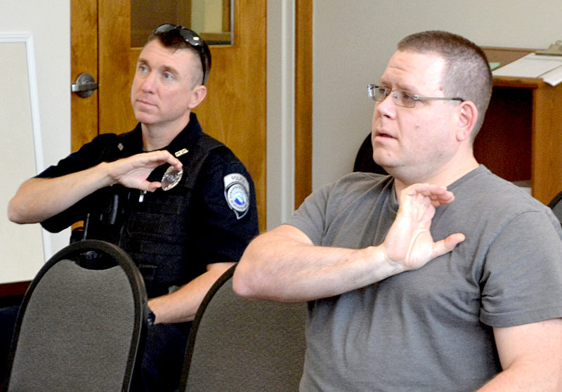 Damariscotta Police Officers Erick Halpin (left) and Jim Dotson practice the sign for police officer during a sign language training session Tuesday, Aug. 2. (Maia Zewert photo)