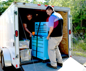 Officer Jim Dotson (left) and Parking Enforcement Officer Westleigh Munroe, of the Damariscotta Police Department, remove a Channellock tool case from a trailer Monday, Aug. 22. The Damariscotta Police Department and the Kennebec County Sheriff's Office filled the trailer and two pickup trucks with items seized from a Randolph home in a theft investigation. (J.W. Oliver photo)