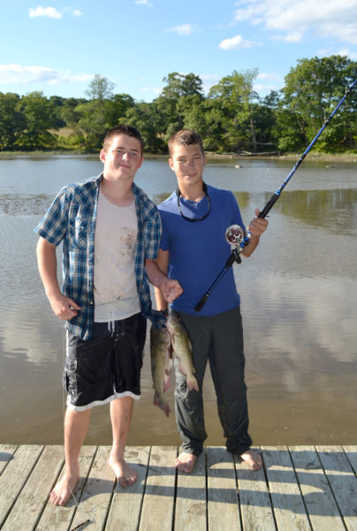 Cole Chapman (left) and Luke Wood hold fish they caught from Mill Brook in Dresden during the Alewife Harvesters of Maine annual pig roast Saturday, Aug. 27. (Maia Zewert photo)