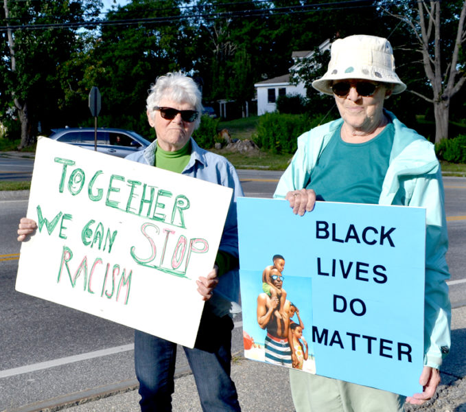 From left: Bobsy Thompson, of Edgecomb, and Suzanne Hedrick, of Nobleboro, participate in a weekly vigil at Veterans Memorial Park in Newcastle to protest racism. "We're trying to stop it and make people more aware about it," Thompson said. (Maia Zewert photo)