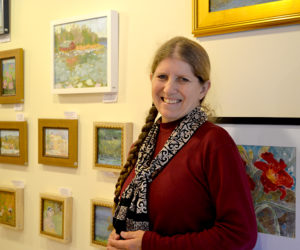 Saltwater Artists Gallery member Alison Dibble stands before a wall featuring her oil and watercolor paintings at the cooperative gallery located in New Harbor. (Christine LaPado-Breglia photo)
