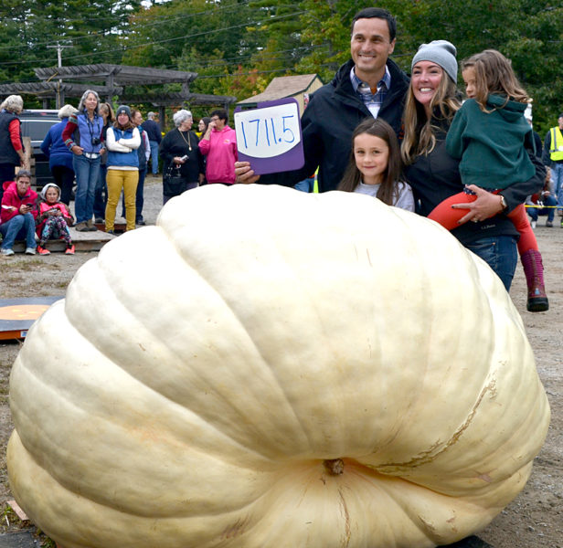 Charlie Lopresti holds a sign declaring the weight of his first-place pumpkin during the Damariscotta Pumpkinfest's annual weigh-off at Pinkham's Plantation in Damariscotta on Sunday, Oct. 2. Lopresti's wife, Morningstar, and daughters, Catherine and Maris, helped grow the pumpkin. (Amber Clark photo)