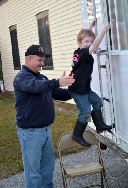 Dresden firefighter Ike Heffron helps Carver Spicer down a ladder after Spicer went through the safety and education smoke trailer at the department's open house Wednesday, Oct. 5. (Abigail Adams photo)