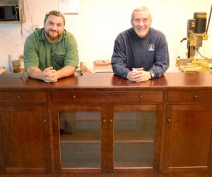 Jesse Daiute (left) and Chris Erickson stand in their Edgecomb workshop with one of their custom pieces of furniture on Thursday, Sept. 29. (Abigail Adams photo)