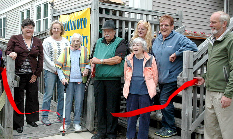 Waldoboro Food Pantry Co-director Lou Cook cuts the ribbon to open the pantry's new location at 251 Jefferson St. From left: Town Manager Linda-Jean Briggs, Tina Cunningham, Jane Lichtman, Cook, Mary Littell (back), Gloria Bowers, Wanda Collamore, and Assessors' Agent Darryl McKenney. (Alexander Violo photo)