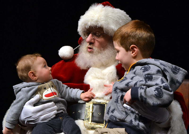 Six-month-old Michael Morgan (left) studies Santa Claus while his brother, Marshall Morgan, 3, asks for a candy cane for Christmas. (Maia Zewert photo)