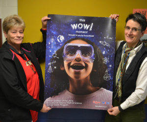 Mr. Mike's Market Manager Dixie Haley (left) and Great Salt Bay Community School Principal Kim Schaff hold an ExxonMobil poster promoting math and science. Haley applied for and recieved a $500 ExxonMobil Education Alliance grant for the school. (Maia Zewert photo)