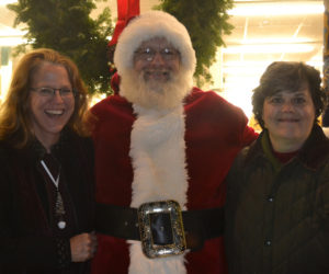 From left: Twin Villages Alliance Chair Mary Kate Reny, Santa Claus, and alliance board member Sarah Maurer celebrate the community and the season during the Wrap It Up street festival Thursday, Dec. 22. (Abigail Adams photo)