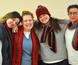 From left: Deanne Donahue, Samantha Tucker, Christa Money, and Byrlynne Ellis model some of the hats and scarves the Two Bridges Regional Jail crochet club will donate to Special Olympics. (Abigail Adams photo)