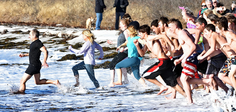 Participants in the eighth annual Pemaquid Polar Bear Dip race into the water at Pemaquid Beach Park on New Year's Day. The event raises funds for the Lincoln County Animal Shelter. (Photo courtesy Sherrie Tucker/sherrietucker.com)