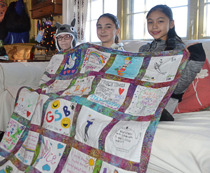 From left: Alice Skiff, Casey Nelson, and Sonny Cumming display a quilt, a gift from Great Salt Bay Community School students and staff to Alice, at the Skiffs' home in Newcastle. (Maia Zewert photo)