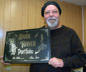 Newcastle artist Glenn Chadbourne displays a copy of his most recent project, "The Dark Tower Portfolio." The collector's item features lithographs of nine original paintings by Chadbourne, including one for each of the eight books in "The Dark Tower" series by Stephen King. (J.W. Oliver photo)