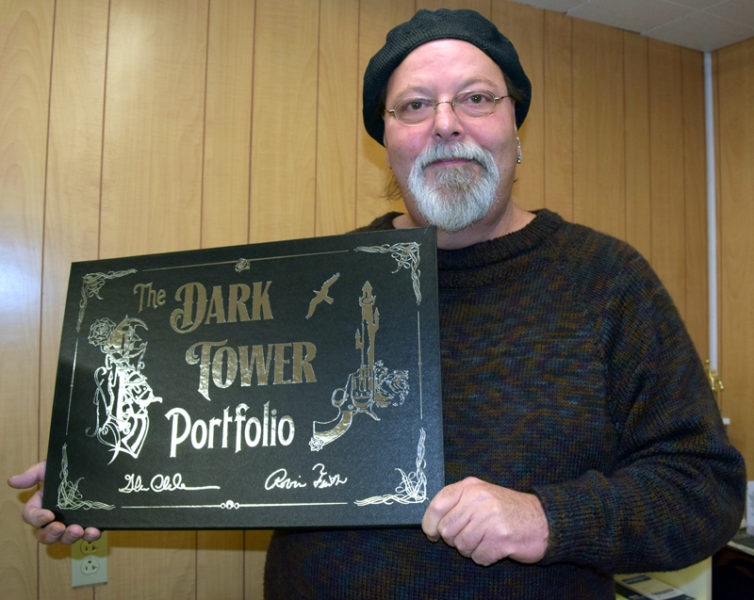 Newcastle artist Glenn Chadbourne displays a copy of his most recent project, "The Dark Tower Portfolio." The collector's item features lithographs of nine original paintings by Chadbourne, including one for each of the eight books in "The Dark Tower" series by Stephen King. (J.W. Oliver photo)