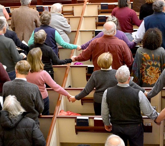 Attendees of a Martin Luther King Jr. Day event at The Second Congregational Church in Newcastle hold hands while singing "We Shall Overcome." (Abigail Adams photo)