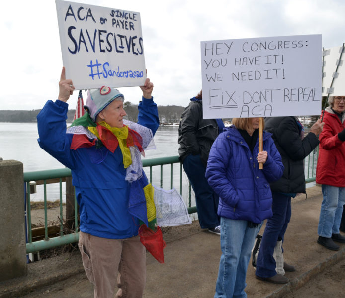 Sharon Sandstrum, an organizer of Lincoln County Indivisible, holds her sign high during a health care-focused protest on the Damariscotta-Newcastle bridge Saturday, Feb. 25. The sign reads "ACA or single payer saves lives #Sanders2020." (Abigail Adams photo)