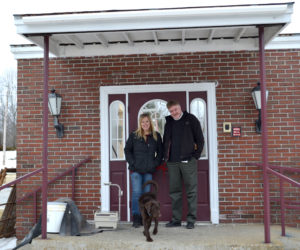 Jan Burns and Jeff Slack stand at the entrance to the Freedom Center with Burns' puppy, Sasha, on Friday, March 24. The original entrance will remain in the rebuilt structure. (Abigail Adams photo)