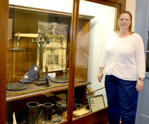 Lincoln County Administrator Carrie Kipfer points out a display cabinet of historic memorabilia at the courthouse. The cabinet will move to another location in the courthouse to make room for the relocation of the registry of deeds. (Charlotte Boynton photo)