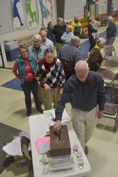 South Bristol residents wait in line to cast their ballots on an warrant article related to the education budget during the annual town meeting at South Bristol School on Thursday, March 16. (Maia Zewert photo)