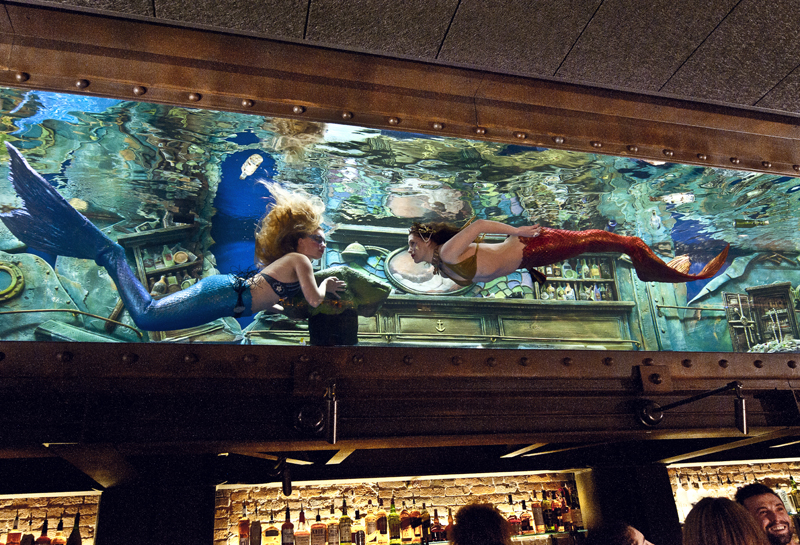 "Mermaids" swim through an aquarium at the Dive Bar in Sacramento, Calif. Tenji Aquarium Design + Build, of Newcastle, Maine and Pacific Grove, Calif., designed and built the 7,500-gallon saltwater aquarium. (Photo courtesy Juan Ayora Photography)