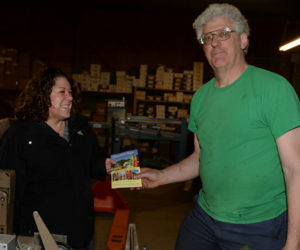 Damariscotta Region Chamber of Commerce Executive Director Stephanie Gallagher picks up the first Damariscotta Region Chamber of Commerce guide from Chris Roberts, of Lincoln County Publishing Co., on Friday, April 14. (Paula Roberts photo)
