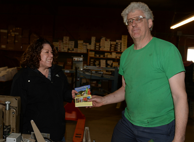 Damariscotta Region Chamber of Commerce Executive Director Stephanie Gallagher picks up the first Damariscotta Region Chamber of Commerce guide from Chris Roberts, of Lincoln County Publishing Co., on Friday, April 14. (Paula Roberts photo)