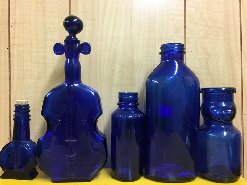 A banjo-shaped bottle (left) and a violin-shaped bottle (second from left) are examples of the variety of old cobalt-blue bottle that collectors treasure.