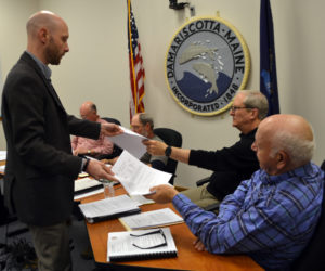 Austin Turner, a civil engineer with Bohler Engineering, distributes copies of the Maine Department of Transporation's permits for two driveways on Damariscotta DG LLC's development to Damariscotta Planning Board members Bruce Garren (center) and Wilder Hunt during the board's Monday, May 1 meeting. (Maia Zewert photo)