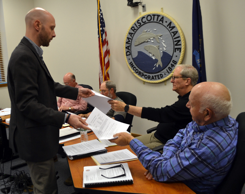 Austin Turner, a civil engineer with Bohler Engineering, distributes copies of the Maine Department of Transporation's permits for two driveways on Damariscotta DG LLC's development to Damariscotta Planning Board members Bruce Garren (center) and Wilder Hunt during the board's Monday, May 1 meeting. (Maia Zewert photo)