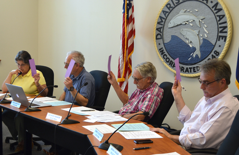 From left: Damariscotta Selectmen Robin Mayer, Ronn Orenstein, George Parker, and Jim Cosgrove vote in favor of the town's secondary education budget during a special town meeting at the town office Wednesday, May 17. (Maia Zewert photo)
