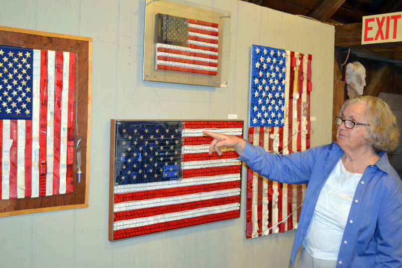 Damariscotta artist Franciska Needham motions to "American Flag in Computer Parts II," one of a number of creatively designed U.S. flags on display at her current show, "America the Beautiful," at her 200-year-old barn-turned-gallery on Water Street. (Christine LaPado-Breglia photo)