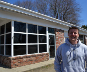 Brendan Parsons stands in front of Damariscotta River Distribution at 68 Main St. in Newcastle. Parsons opened the oyster distribution business in March and is in the process of converting the rest of the building into a raw bar and retail shop, The Shuck Station. (Maia Zewert photo)