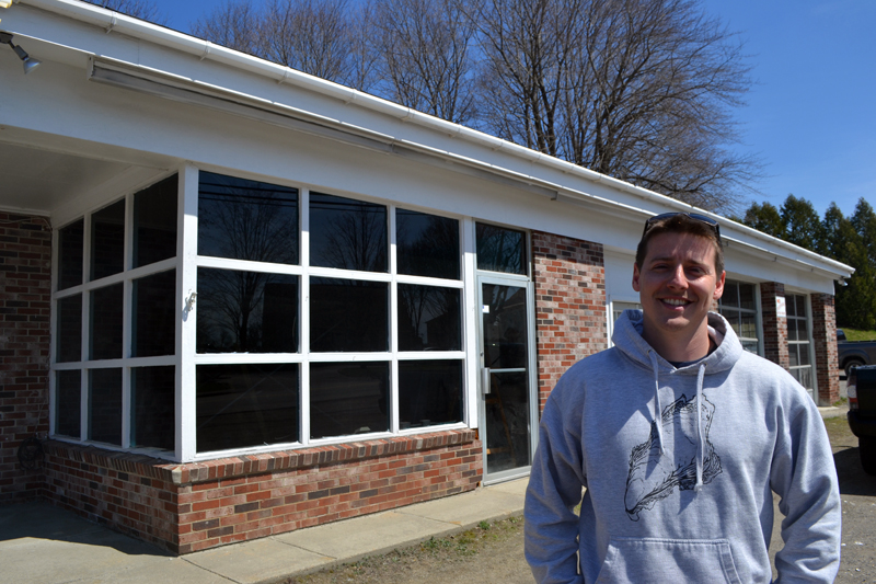 Brendan Parsons stands in front of Damariscotta River Distribution at 68 Main St. in Newcastle. Parsons opened the oyster distribution business in March and is in the process of converting the rest of the building into a raw bar and retail shop, The Shuck Station. (Maia Zewert photo)