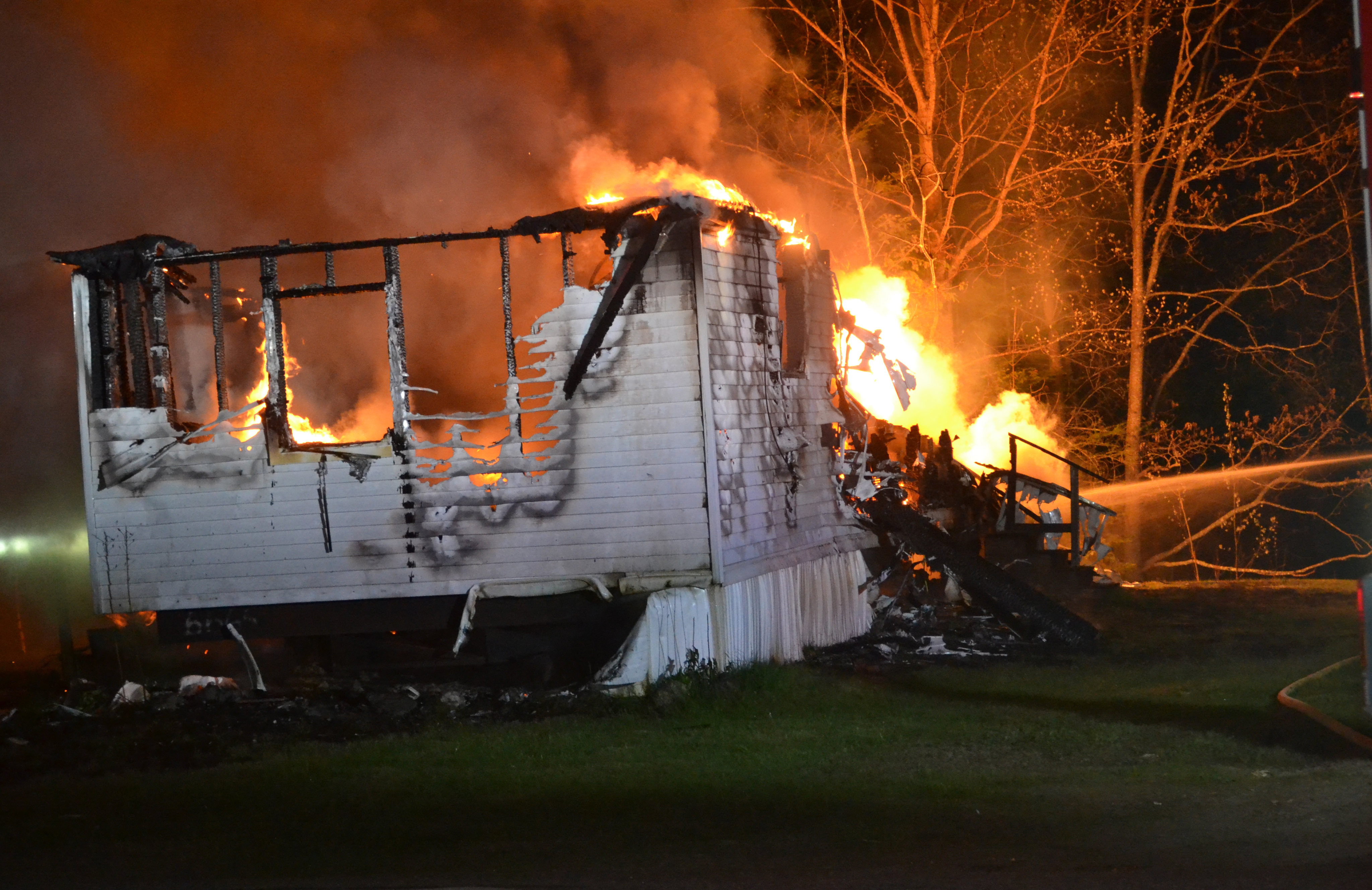 Flames rise from propane tanks behind a mobile home at Brookside Mobile Home Park in Waldoboro as firefighters work to prevent the spread of the fire to neighboring structures early Saturday, May 20. (Abigail Adams photo)